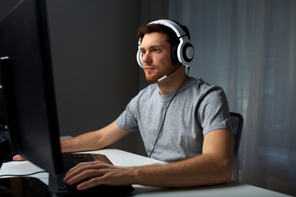 Closeup de homem com fone de ouvido para jogos jogando jogo de ação online  multiplayer usando configuração de pc profissional no torneio. jogador  olhando para a tela do computador enquanto conversa com