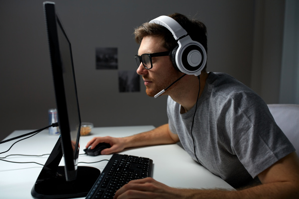 Closeup de homem com fone de ouvido para jogos jogando jogo de ação online  multiplayer usando configuração de pc profissional no torneio. jogador  olhando para a tela do computador enquanto conversa com