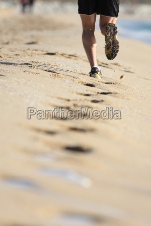 Pernas de homem correndo na areia de uma praia - Fotos de arquivo #8451005