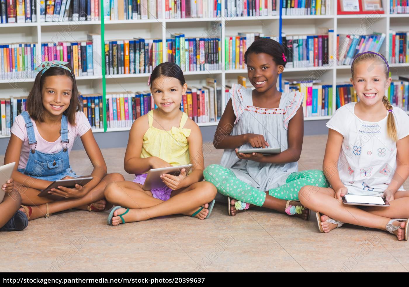 menina bonitinha sentada no chão usando tablet digital tocando a