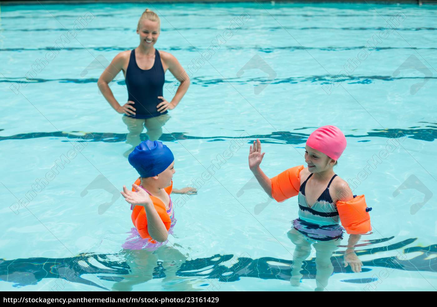 Mulher instrutora de natação mostra à menina como nadar com